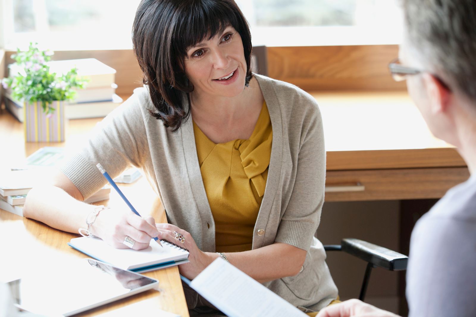 A hiring chiropractor reviews a woman's resume as they both sit at a desk.