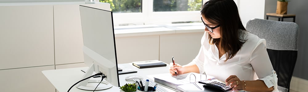 A woman with a calculator reviews cash flow numbers in a binder.