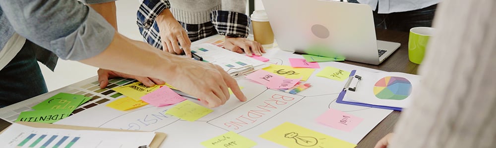 A group of people review a marketing plan covered in sticky notes.